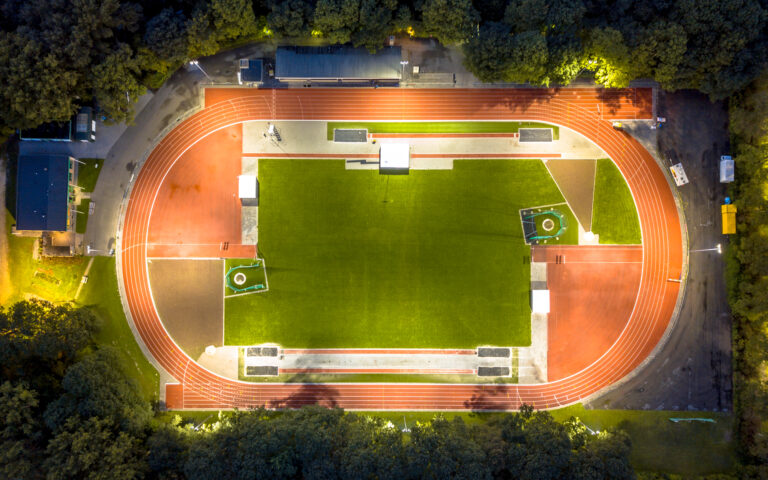 Aerial view of running track where athletics are training at night under bright stadium lights