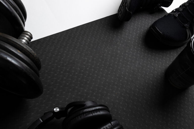 The fitness background with dumbbells, earphones, shoe on a black mat