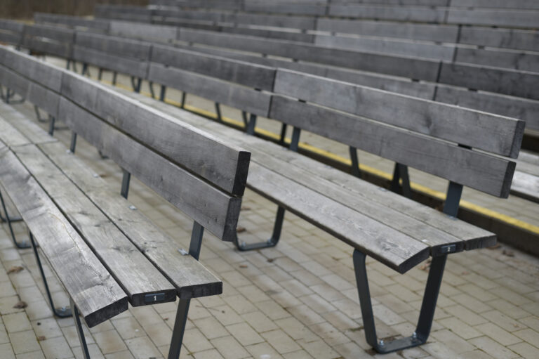 Open air stage and seating for the audience, rows of grey wooden benches