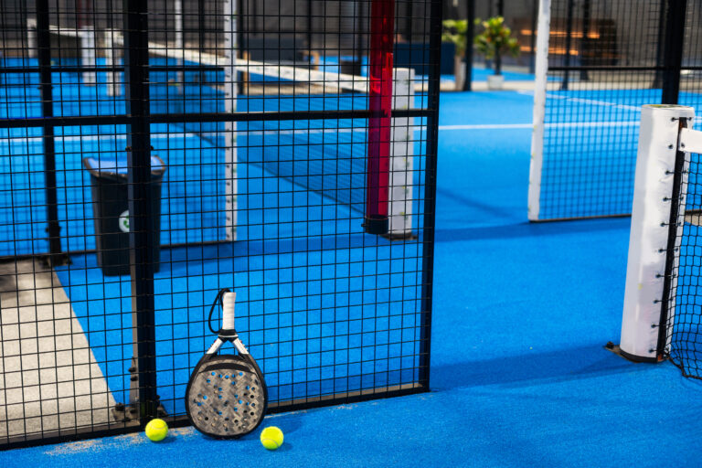 Paddle tennis racket, ball and net on the court . High quality photo