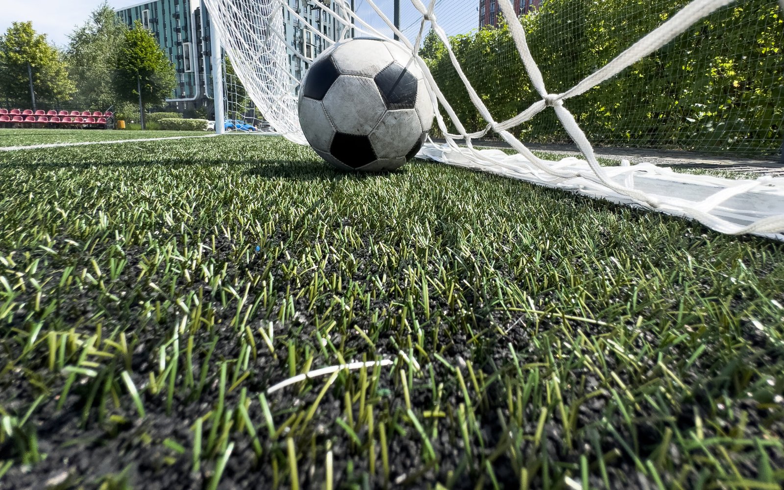Soccer football in Goal net with green grass field. For sport concept. High quality photo