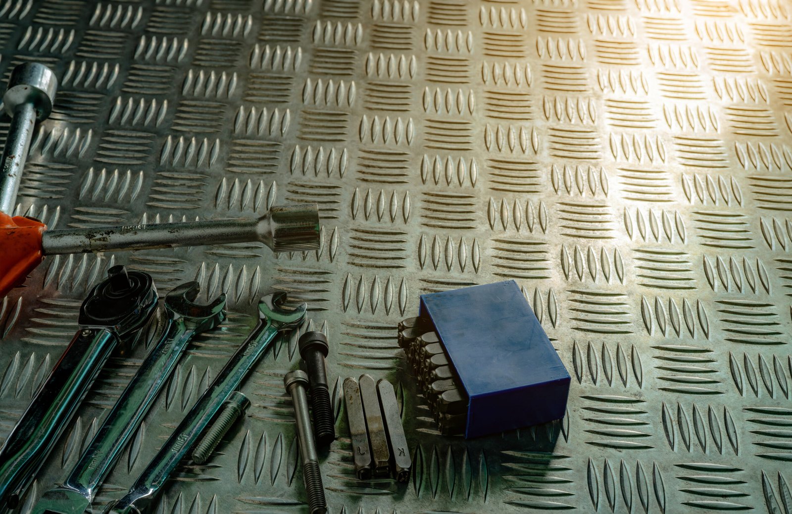 Top view of tools on industrial metal checker plate. Metal checkerplate for anti skid. Nut, bolts, and hex key on metal sheet floor. Silver bump ground with art pattern. Silver texture background.