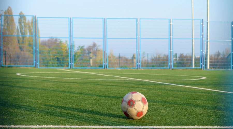 Classic soccer ball on football green grass field outdoor. Active sports and physical training concept