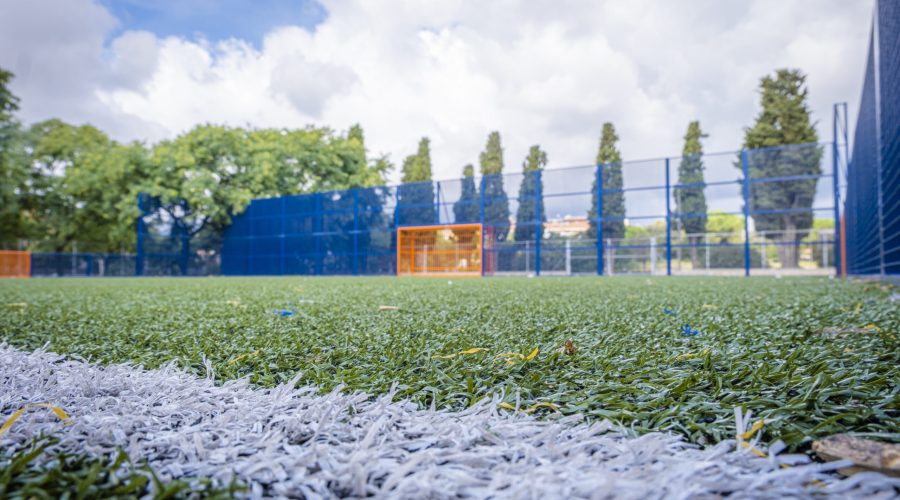 Close-up of the artificial grass of a soccer field With the goal out of focus in the background.