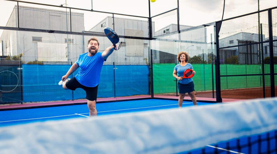 Mixed adult couple palying padel on outdoor court.